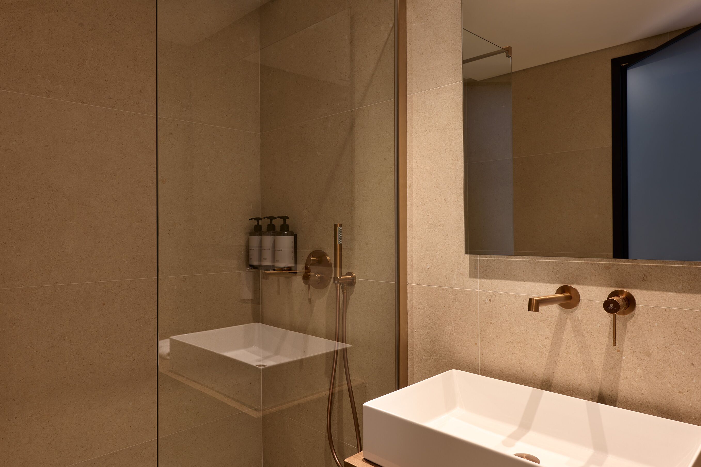 A modern bathroom with a glass-enclosed shower, a white sink, and a large mirror.