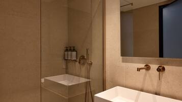 Un baño moderno con ducha de vidrio, lavamanos blanco y espejo grande.