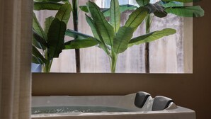A spa area with a bathtub and large green plants in the background.