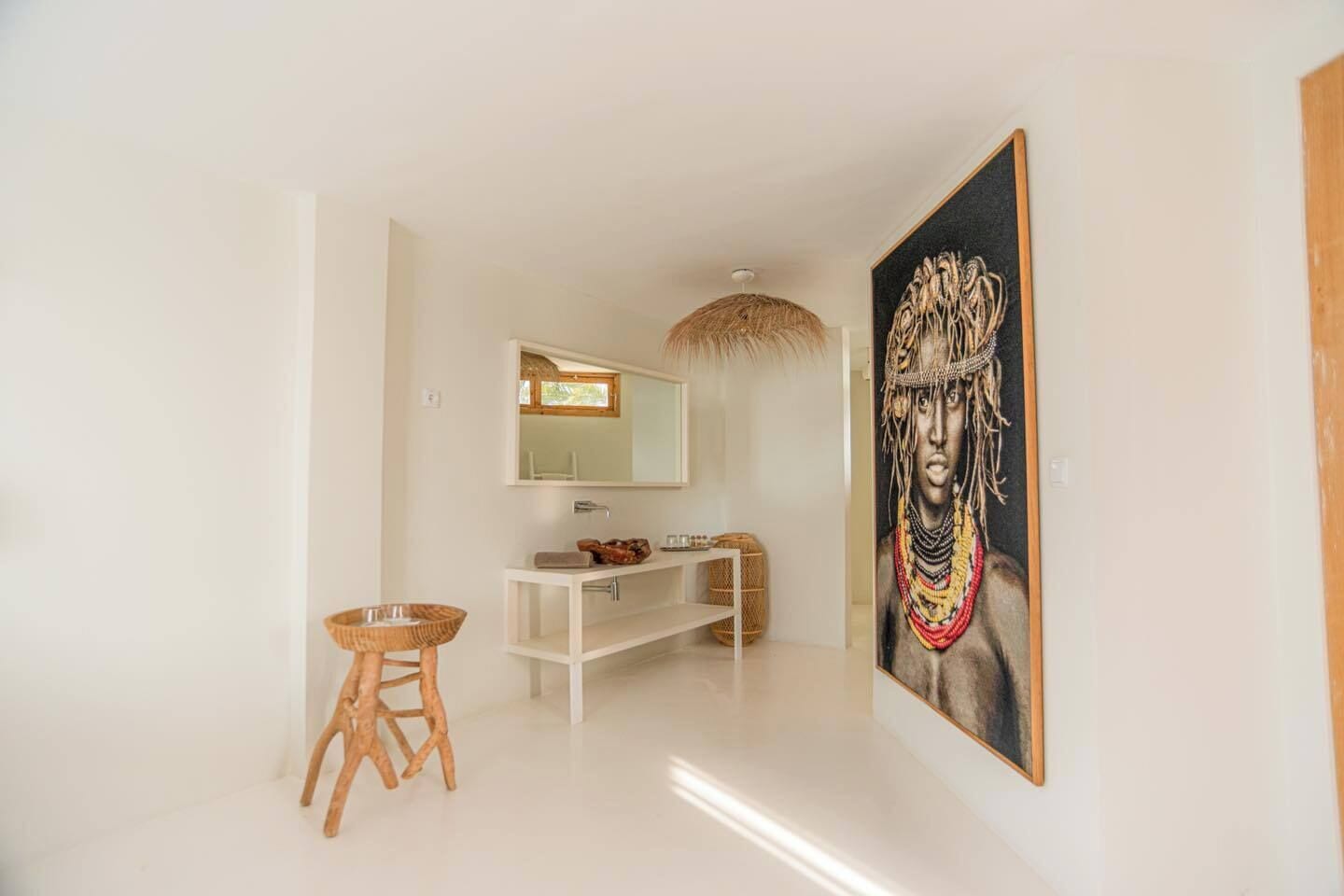 Un baño moderno con un tocador blanco, un taburete de madera y un cuadro grande en la pared.