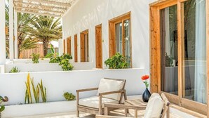 Un espace extérieur aménagé, abrité et doté de mobilier en bois et de plantes en pot.