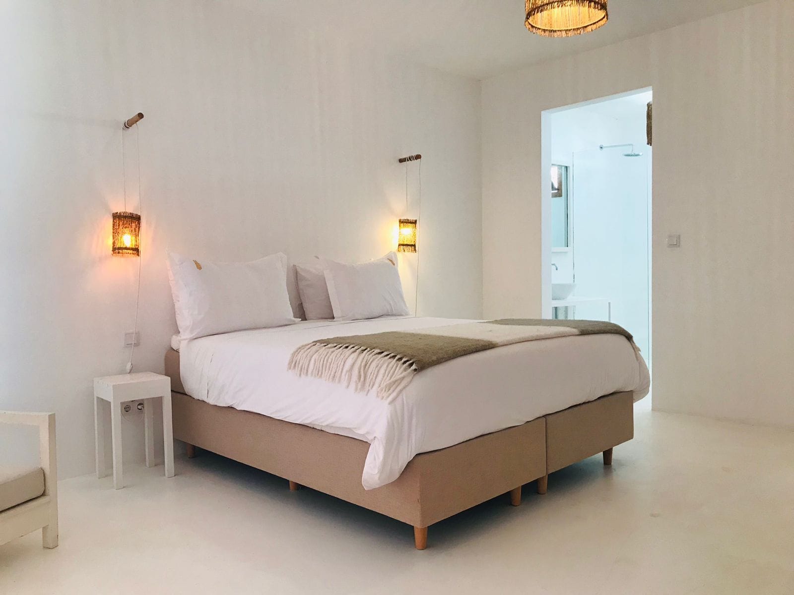 A modern bedroom with a large bed, two bedside tables, and wall-mounted lighting.