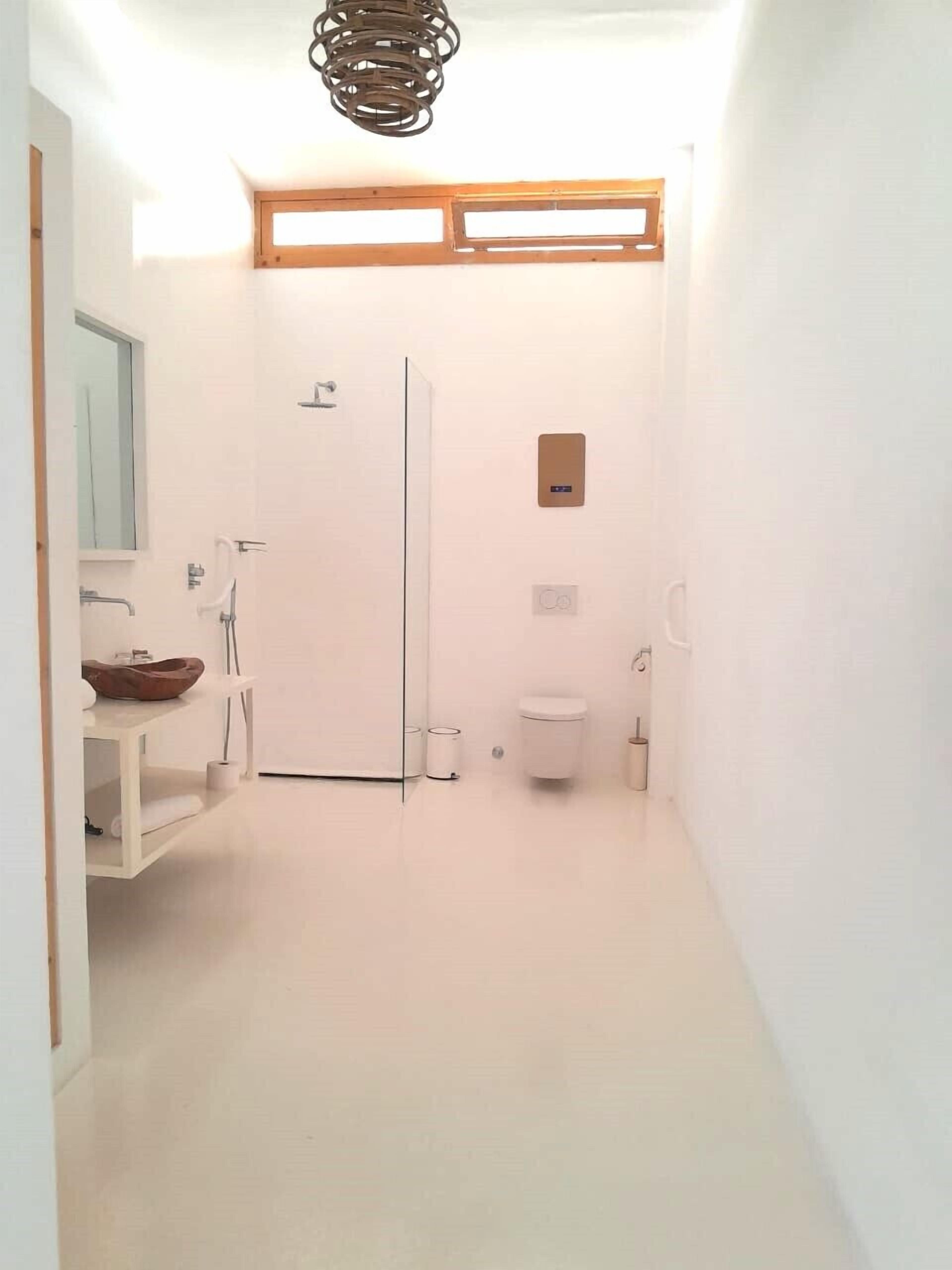 Un couloir étroit menant à une salle de bain équipée de toilettes, d’un lavabo et d’un miroir.