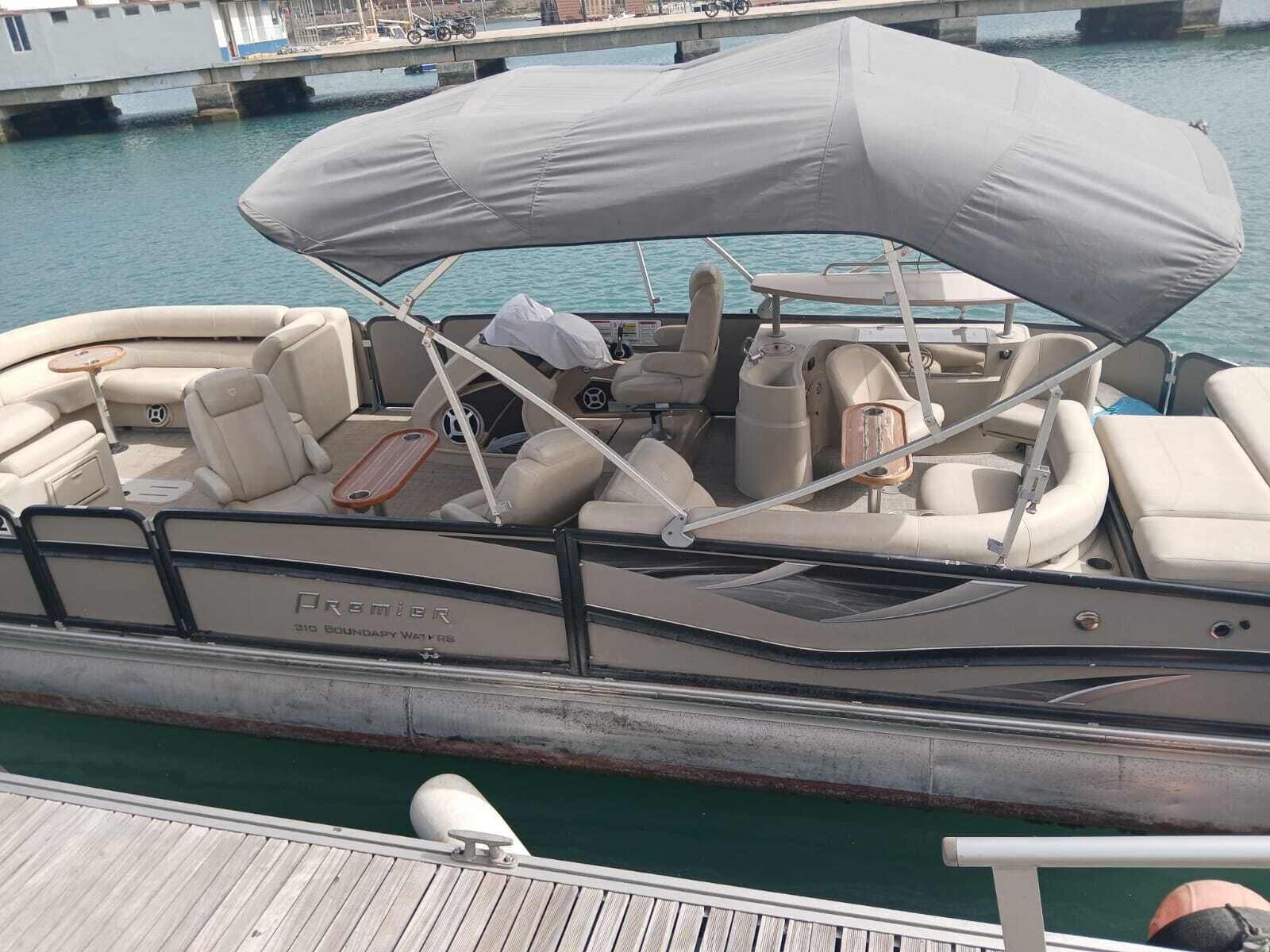 A boat with a covered seating area, a steering wheel, and a small table.