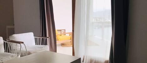 A hotel room with a bed, a small table, and a view of a balcony with a chair.