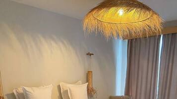 A modern bedroom with a large bed, a woven ceiling light fixture, a bedside table, and a view of the outdoors.