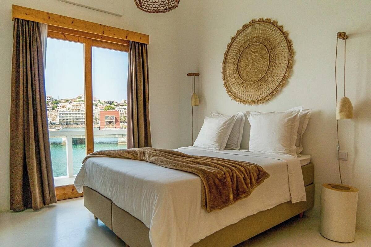 Un dormitorio con una cama, vistas a un paisaje urbano y un tapiz tejido en la pared.
