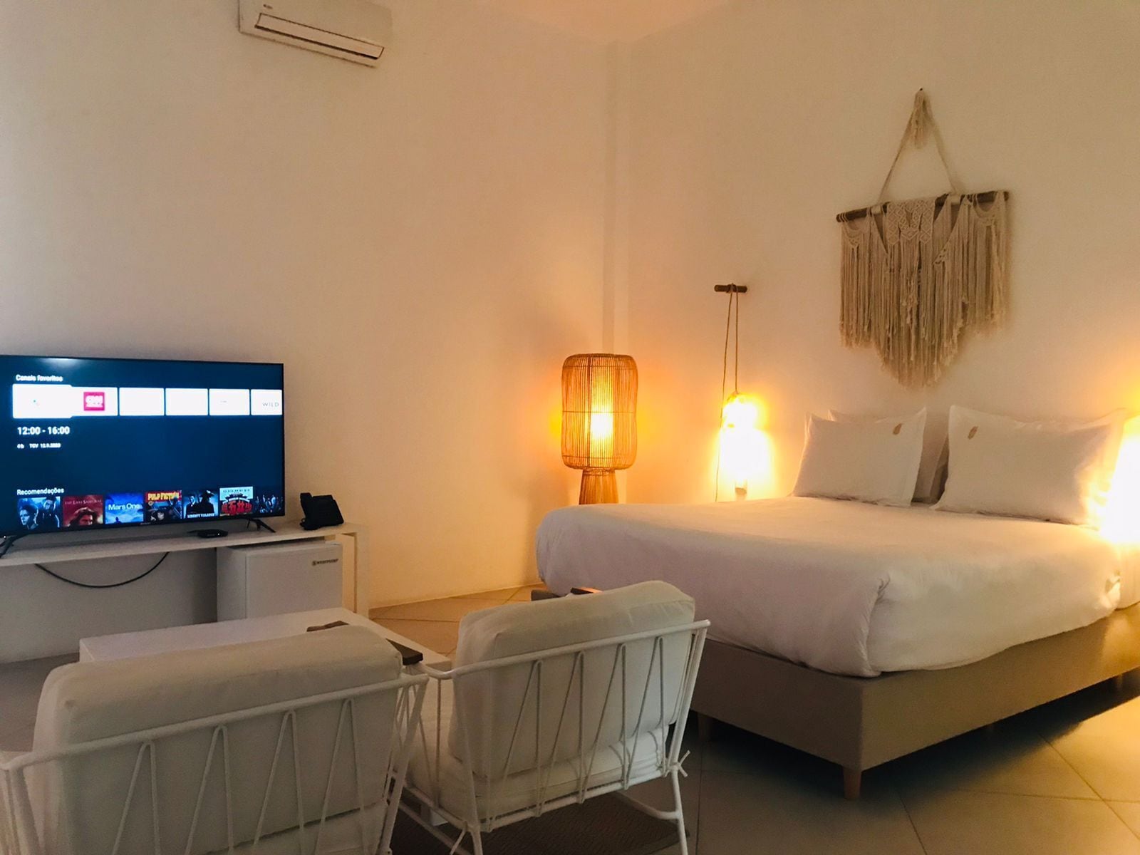 Une chambre d’hôtel avec un lit, des lampes de chevet, un téléviseur posé sur un bureau et une chaise.