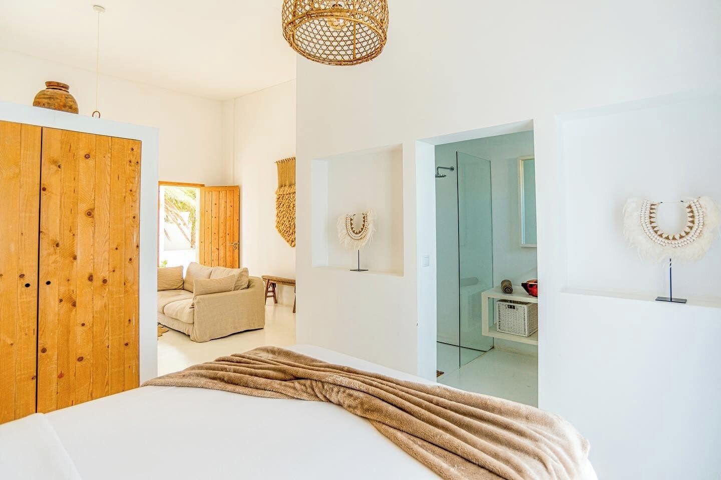 Une chambre à coucher avec un grand lit, une armoire en bois et un luminaire suspendu.