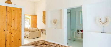 A bedroom with a large bed, wooden wardrobe, and a hanging light fixture.