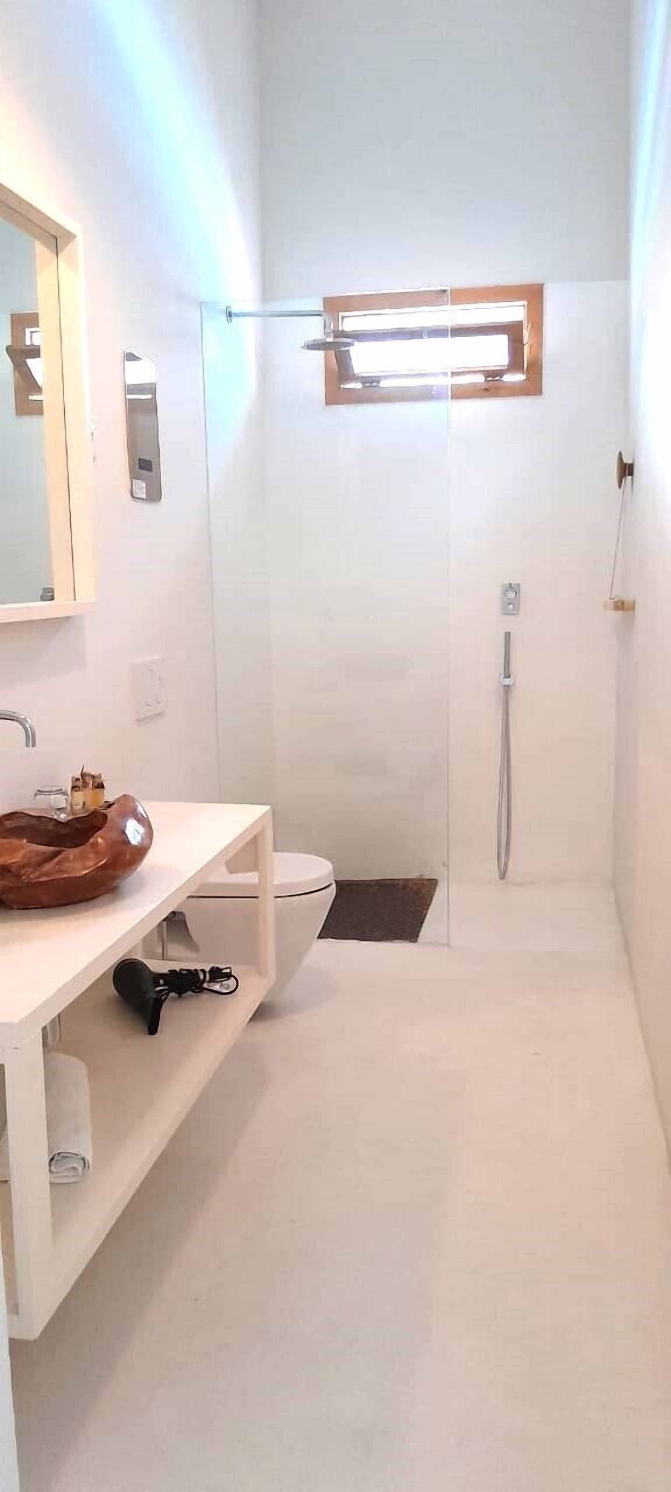 A modern bathroom with a white vanity, a large mirror, and a shower area.