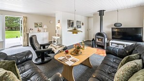 A modern living room with a fireplace, leather sofas, a coffee table, and a television.