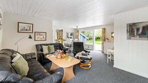 A modern living room with a black leather sofa, a wooden coffee table, and a dining area with a table and chairs.