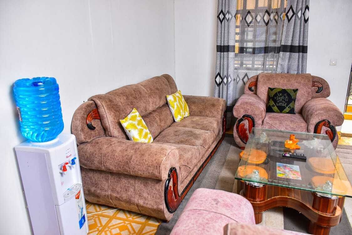 A living room with a brown sofa, a glass coffee table, and a water dispenser.