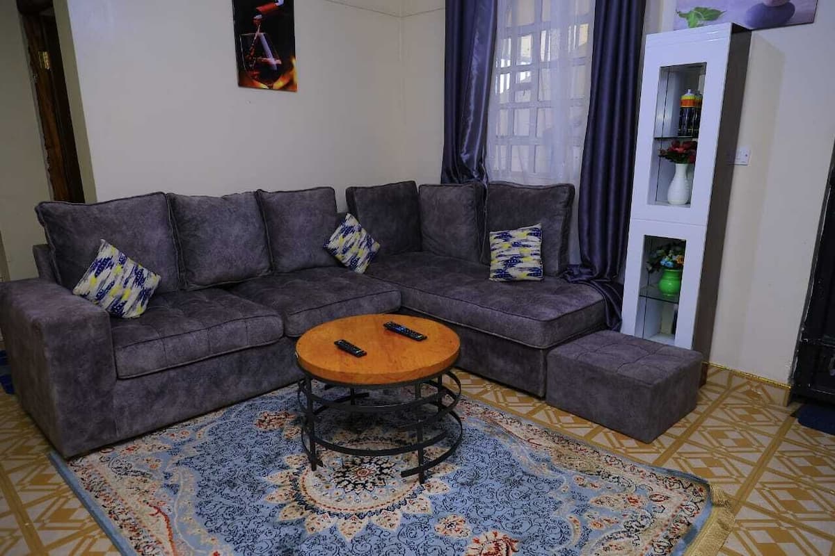 A living room with a grey sectional sofa, a round coffee table, and a patterned rug.