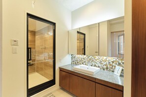 Bathroom features a glass-enclosed shower, sink with a rectangular basin, and a mosaic-patterned backsplash.