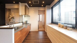 Una cocina moderna con encimera de madera, pileta de acero inoxidable y ventana con persianas.