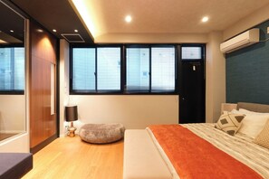 Relax in a serene bedroom with a large bed, ottoman, and reading lamp.