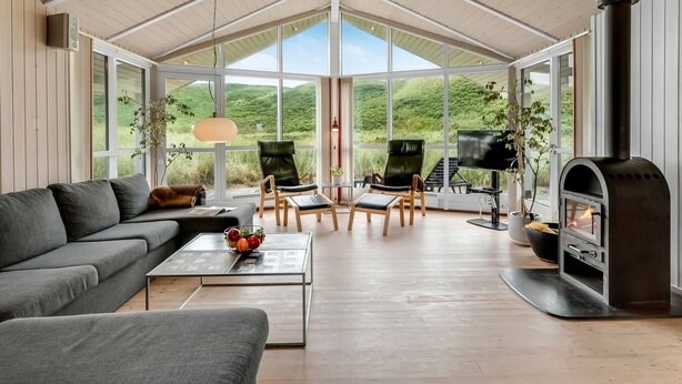 A modern living room with a large fireplace, comfortable seating, and a view of the outdoors.