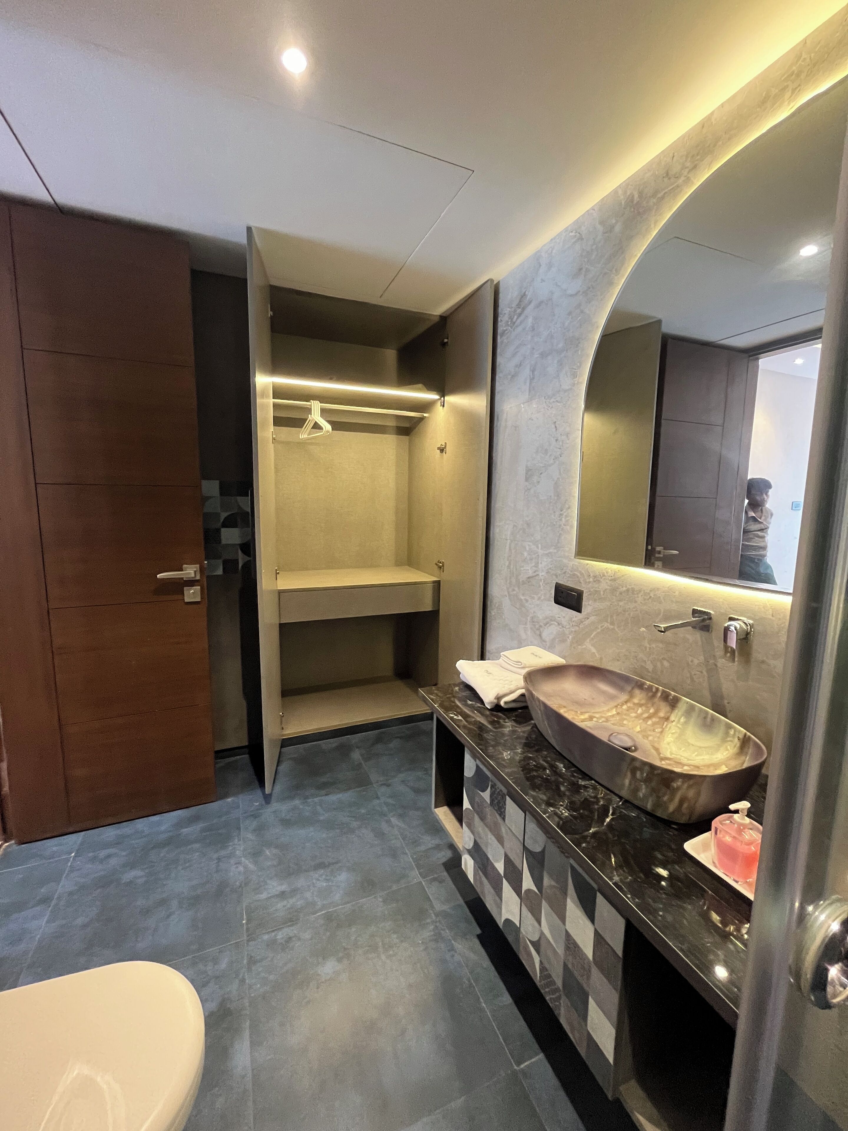 Un baño moderno con lavamanos de mármol, ducha integrada y un espejo grande.