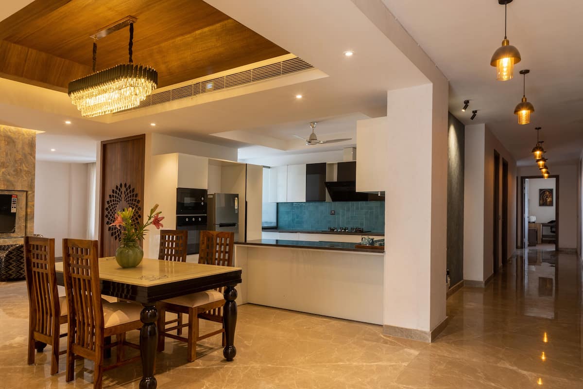 A modern kitchen with a central island, wooden dining table, and chairs.