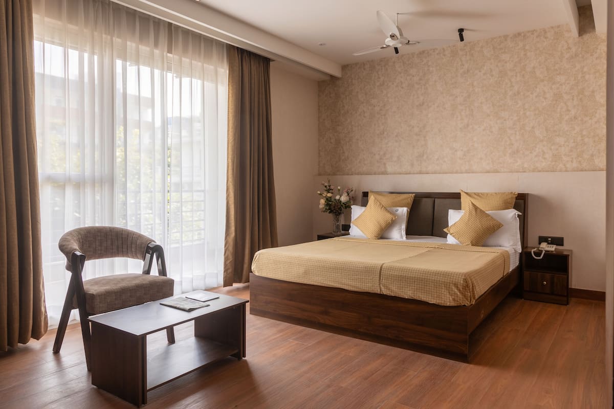 A modern bedroom with a large bed, a chair, a bedside table, and a nightstand.