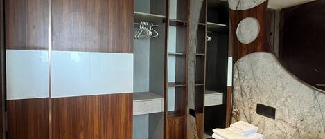 A modern bathroom with a wooden vanity, a large mirror, and a marble backsplash.