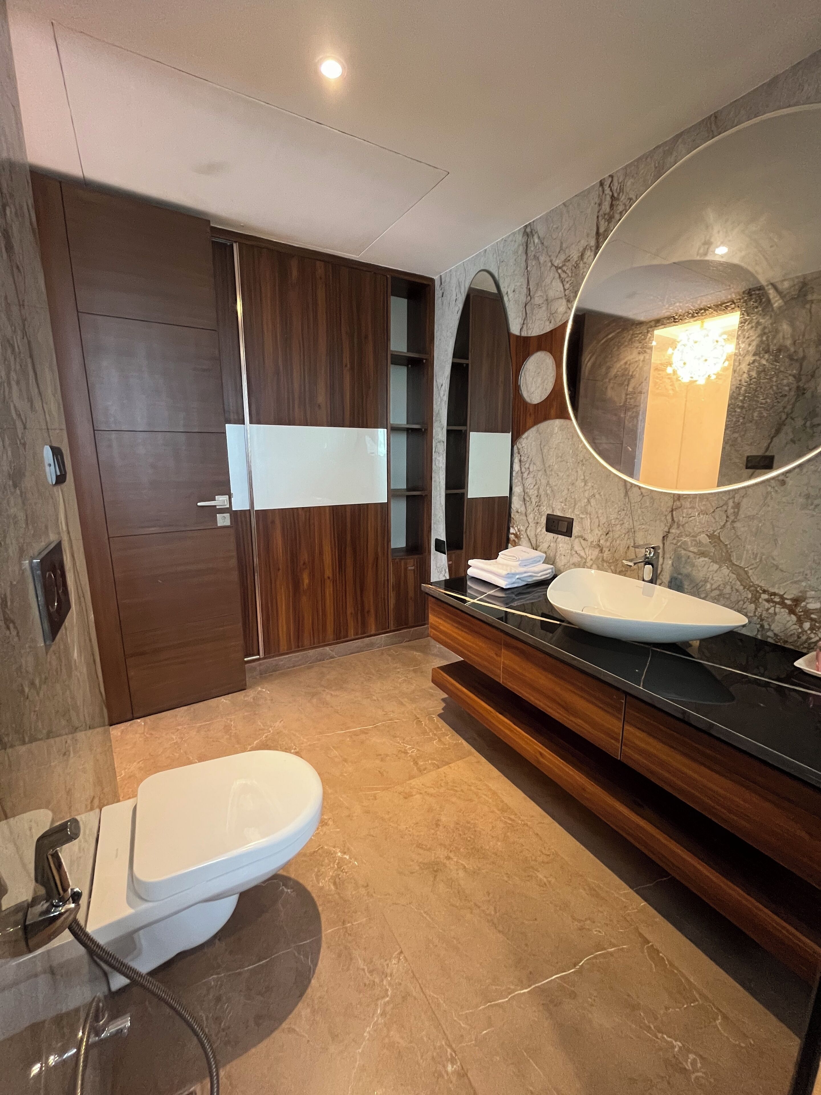 Un baño moderno con un espejo grande, un inodoro blanco, un mueble de tocador con lavabo y una zona de ducha.