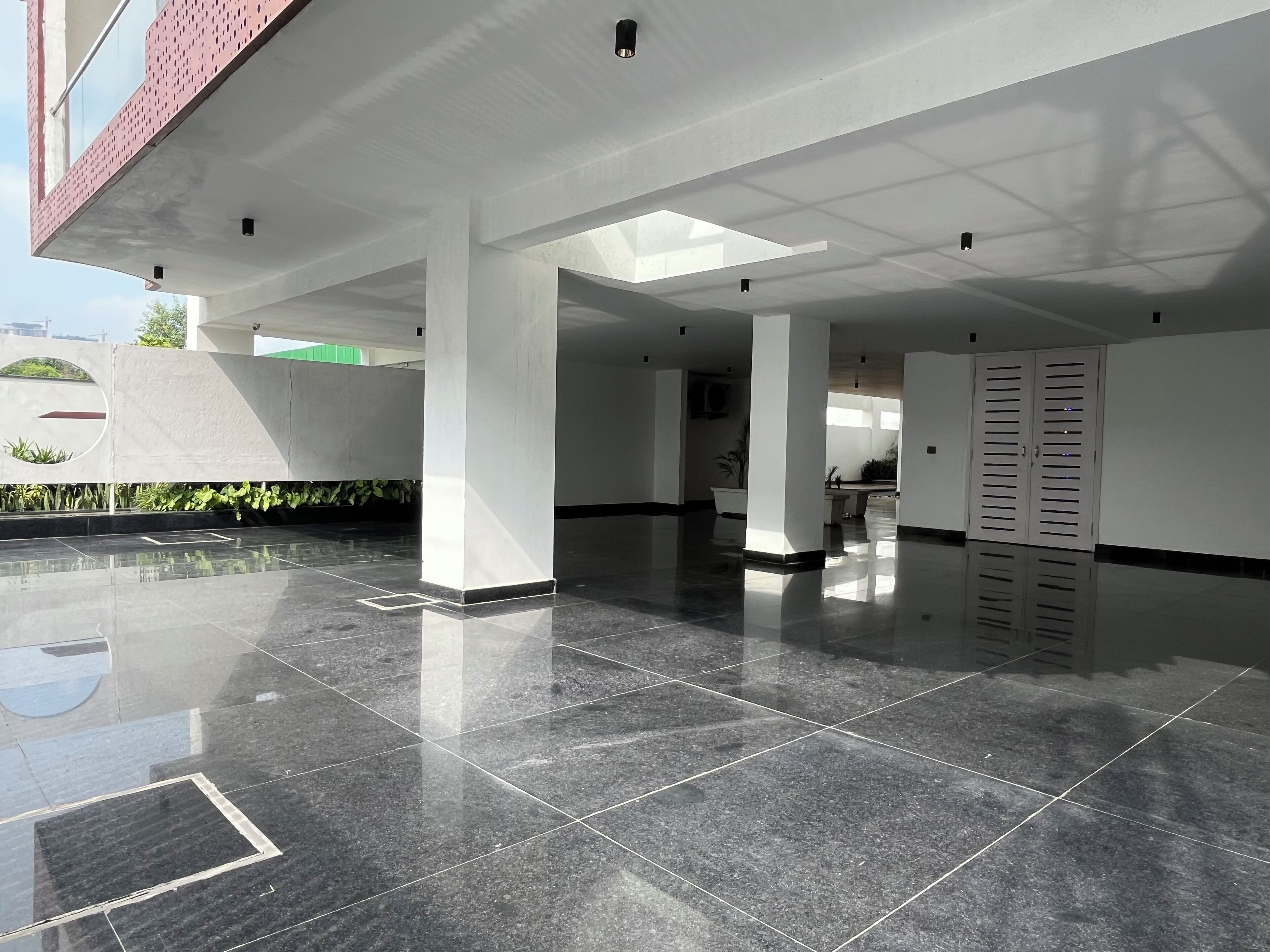 A spacious indoor area with a polished tile floor, white pillars, and a large door with a window.