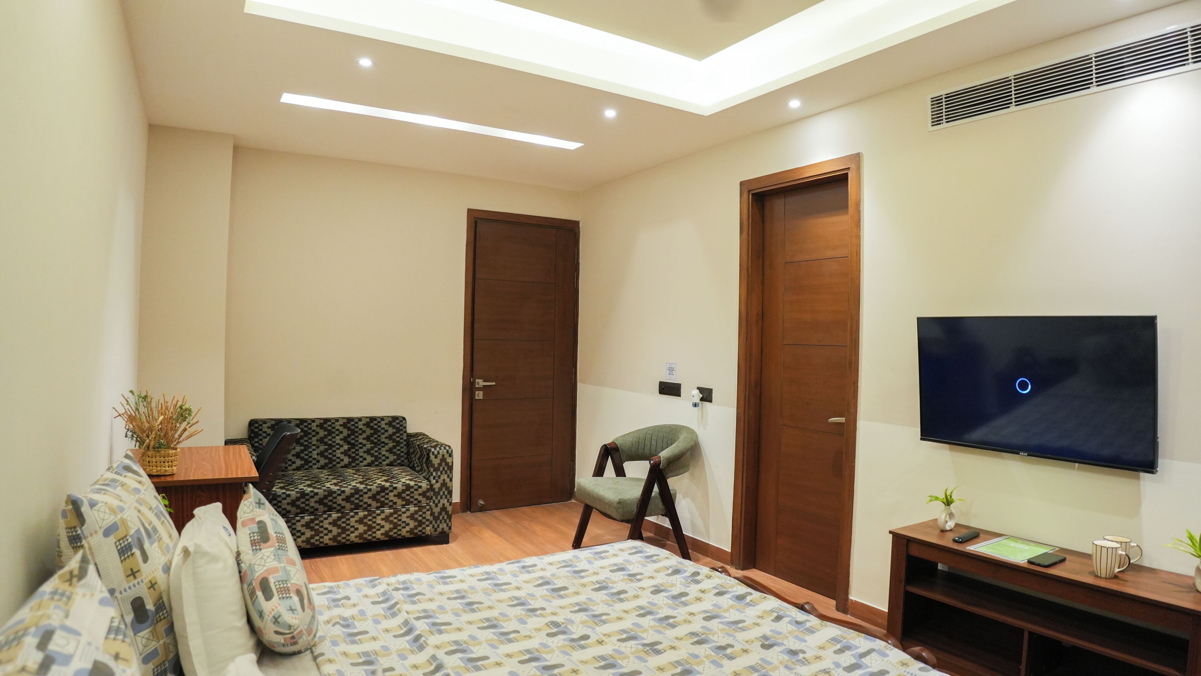 Un dormitorio moderno con una cama, un sofá, una silla, un televisor y un escritorio.