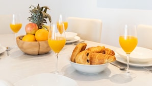 A breakfast table with croissants, fruit, and orange juice glasses. - Stylish 2BR 2BA by the Heart of Soho (London)