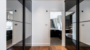 A modern interior with a wooden floor, a kitchen with dark cabinetry, and a bathroom with a bathtub. - Stylish 2BR 2BA by the Heart of Soho (London)