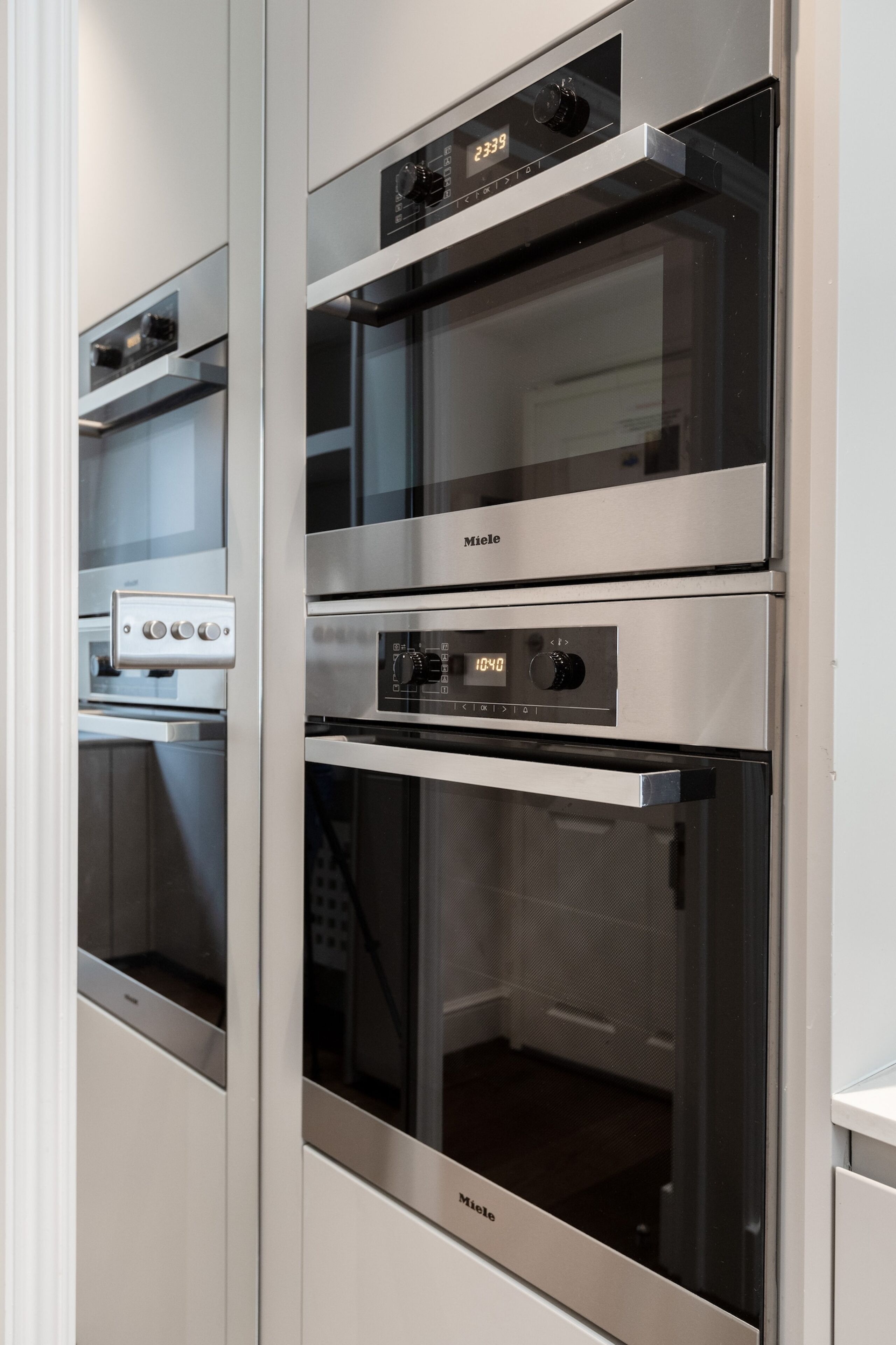 A kitchen with three stainless steel ovens, each with a digital display.