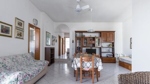 A spacious living area with a sofa, dining table, and chairs, a kitchen with cabinets and a dining table, and a bedroom with a bed and nightstand. - 4174 Villetta Olmo by Barbarhouse (Porto Cesareo)