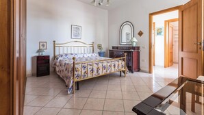 A bedroom with a bed, bedside tables, a dresser, a mirror, and a door leading to another room. - 4174 Villetta Olmo by Barbarhouse (Porto Cesareo)