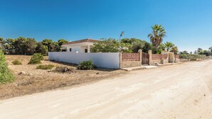 A single-story house with a white exterior and a red-tiled roof, surrounded by a low wall and a gated entrance. - 4174 Villetta Olmo by Barbarhouse (Porto Cesareo)