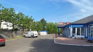 A KFC restaurant with a blue exterior, a paved parking area, and a white van parked in front. - Parc Hotel (Carrieres-sous-Poissy)