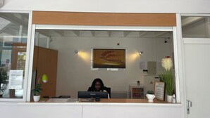 A reception desk with a computer, a potted plant, and a framed sign. - Parc Hotel (Carrieres-sous-Poissy)