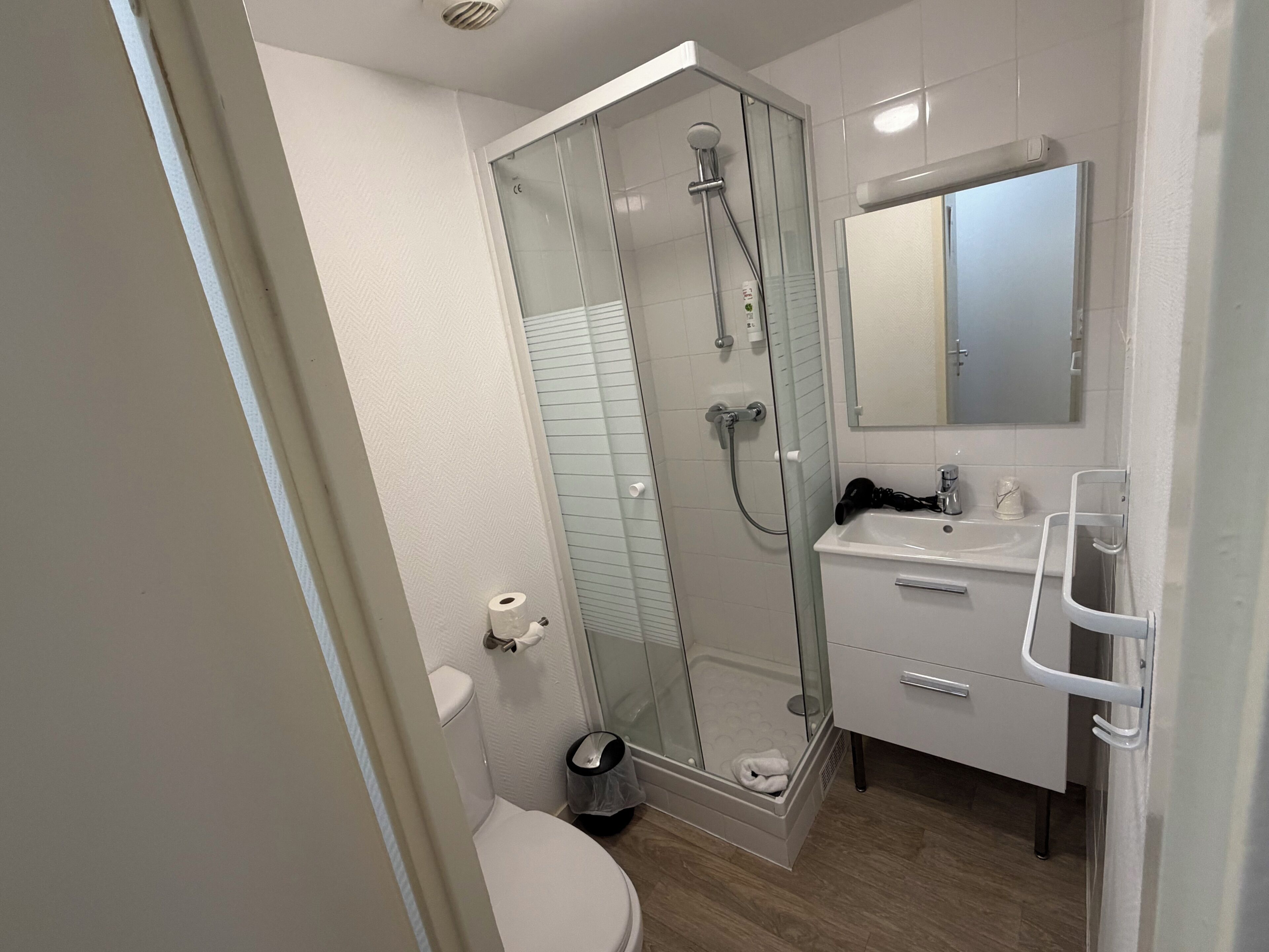 Un baño moderno con ducha envuelta en vidrio, inodoro blanco y tocador con espejo.