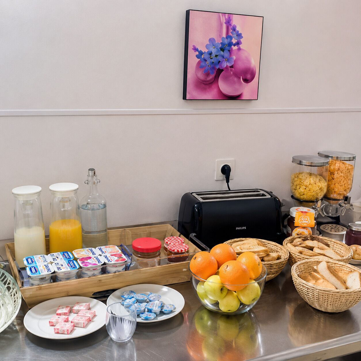 A breakfast buffet setup with various food items, a toaster, and condiments.