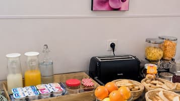 A breakfast buffet setup with various food items, a toaster, and condiments.