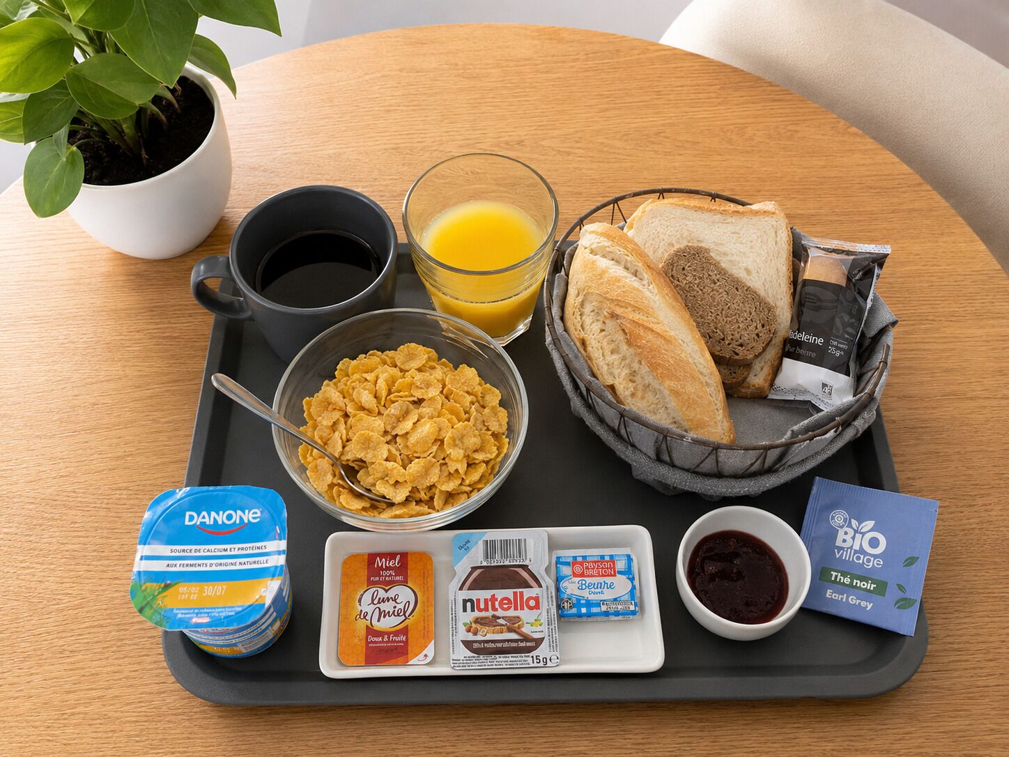 A breakfast tray with cereal, bread, juice, coffee, and spreads.