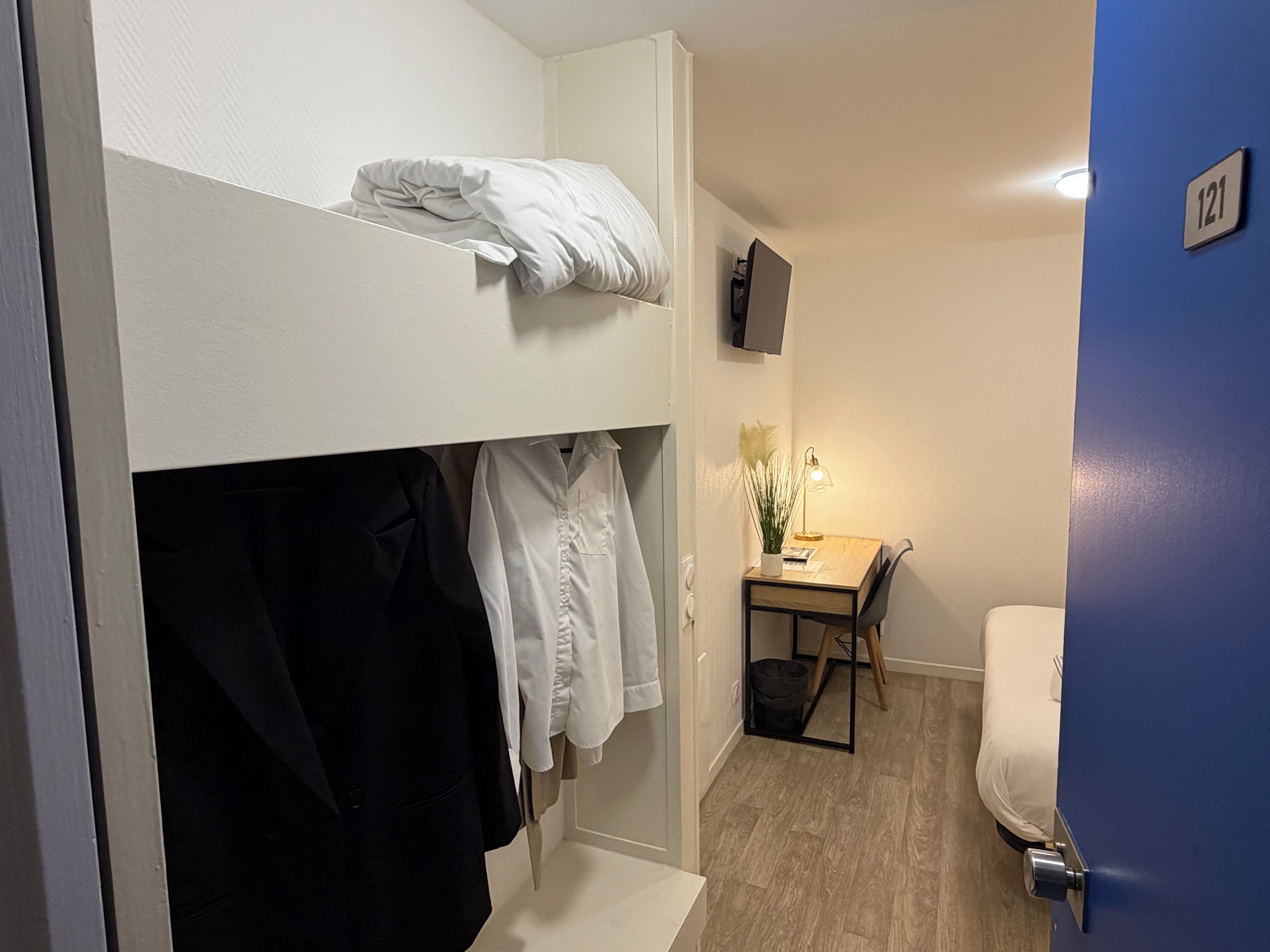 Una habitación pequeña con una cama litera, un escritorio con lámpara y una silla.