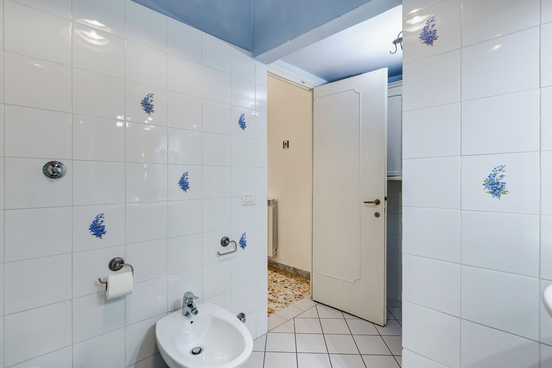 Une salle de bain avec des carreaux blancs, un lavabo et des toilettes.