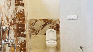 Un baño con ducha, inodoro y un balde.