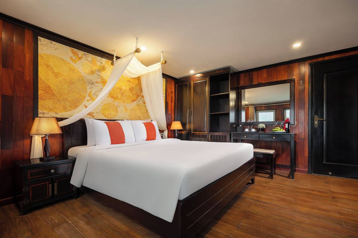 A spacious bedroom with a large bed, a nightstand, a dresser, and a vanity with a mirror.
