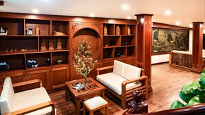 Una amplia biblioteca con estanterías de madera, una zona de estar acogedora y un gran ventanal con vista a un barco.
