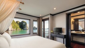 Quarto de hotel com cama grande, televisão, secretária com computador e banheiro com espelho e pia.