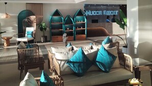 A spacious lobby with wicker furniture, a reception desk, and a sign for 'Hudson Resort'. - Hudor Resort (Bauang)