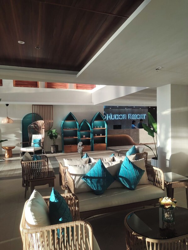 A spacious lobby with wicker furniture, a reception desk, and a sign for 'Hudson Resort'. - Hudor Resort (Bauang)